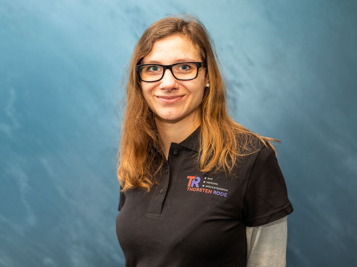 Eine Frau mit Brille und schwarzem Hemd lächelt in die Kamera.