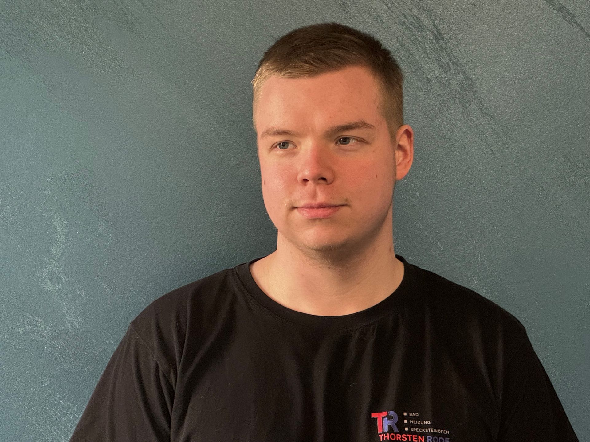 Ein Mann trägt ein schwarzes T-Shirt mit dem Buchstaben R darauf