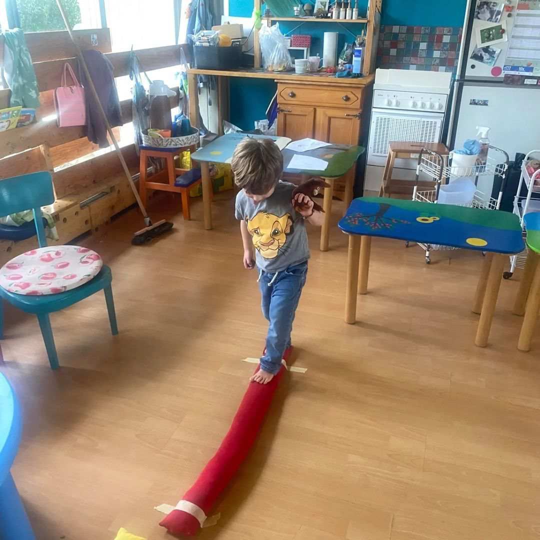 Un petit garçon marche sur un tube rouge dans une pièce