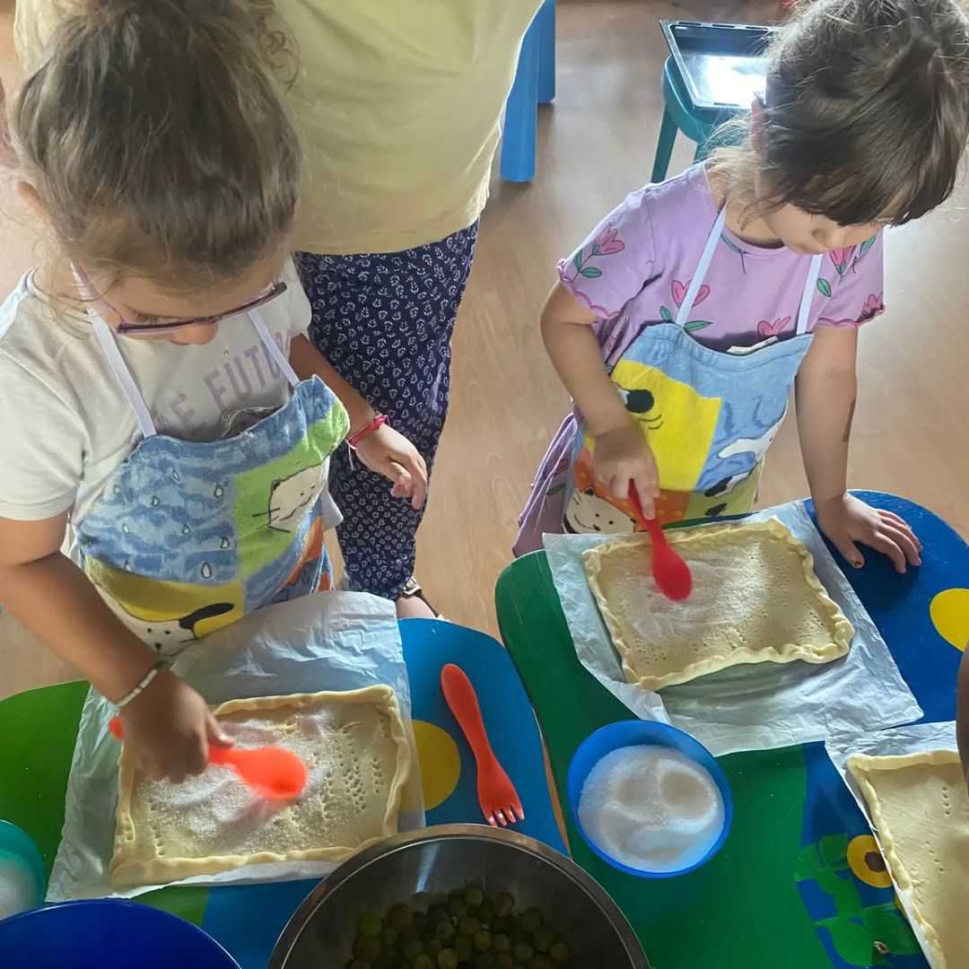 Deux petites filles en tablier préparent de la nourriture à une table