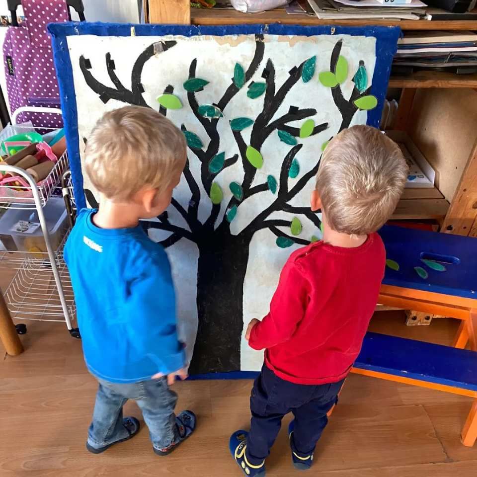 Deux jeunes garçons se tiennent devant une peinture représentant un arbre