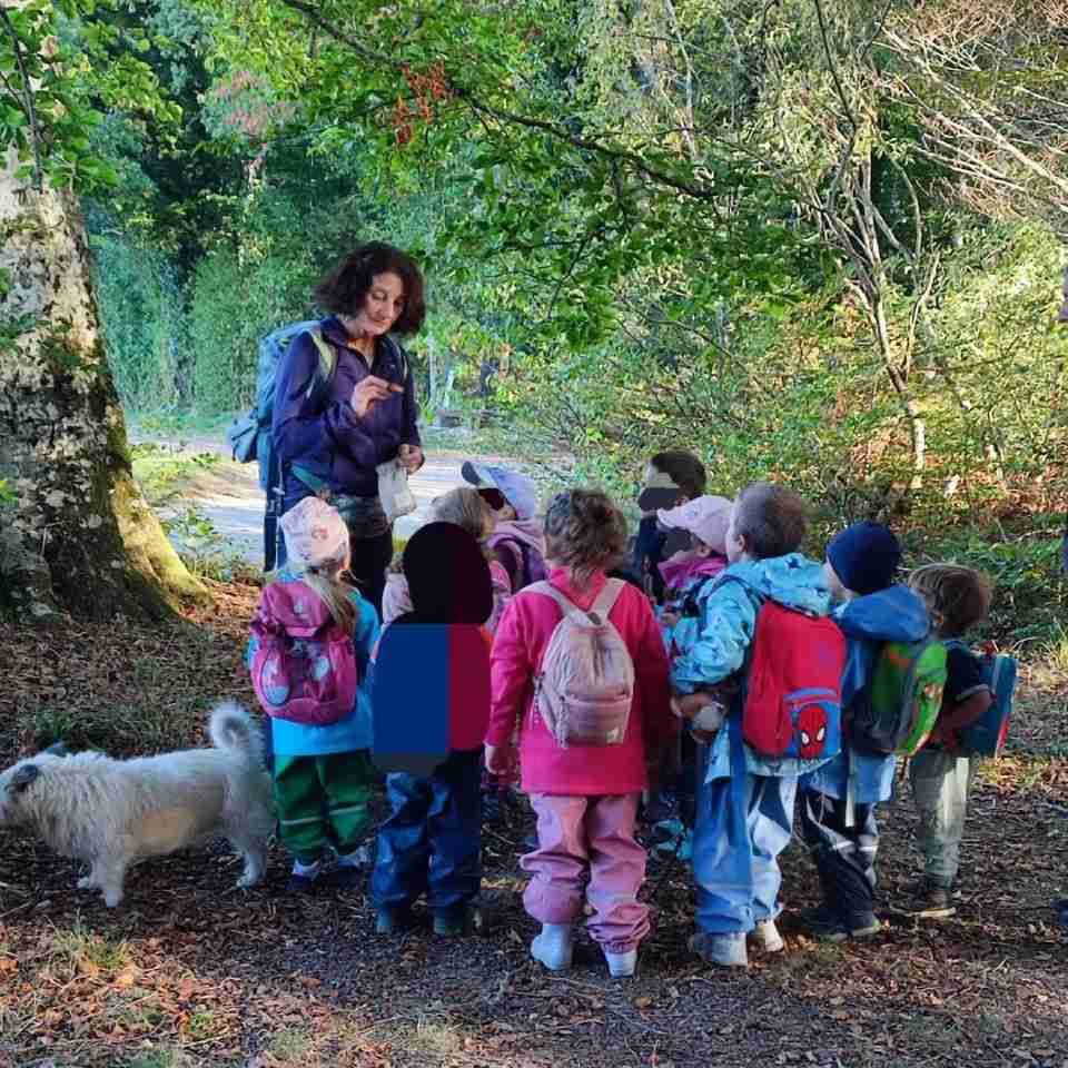Une femme parle à un groupe d'enfants dans les bois.