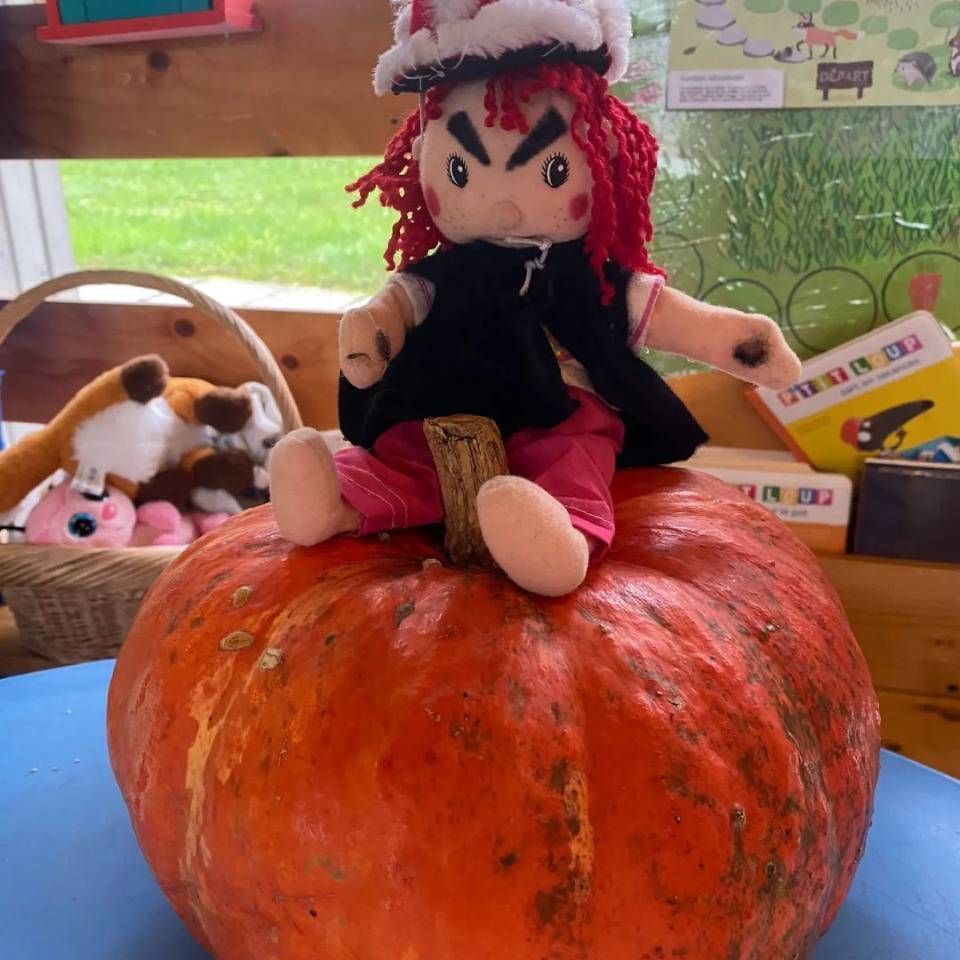 Une poupée en peluche est assise sur une citrouille orange