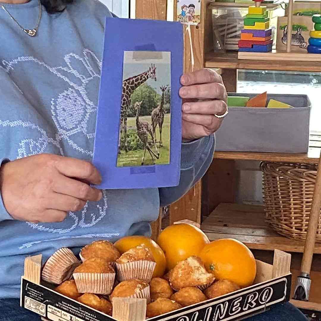Une personne tenant une photo d'une girafe à côté d'une boîte d'oranges