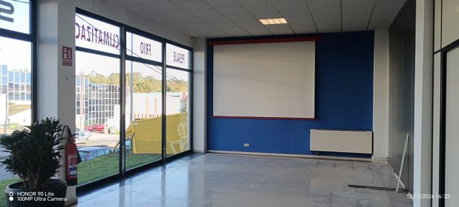Una gran sala vacía con una pantalla de proyector en la pared.