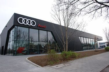 Ein großes Audi-Autohaus mit vielen Fenstern und Bäumen davor.