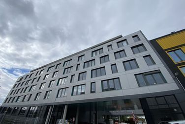 Ein großes Gebäude mit vielen Fenstern und einem gelben Gebäude im Hintergrund.