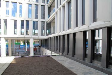 Ein großes Gebäude mit vielen Fenstern und einem Innenhof davor.