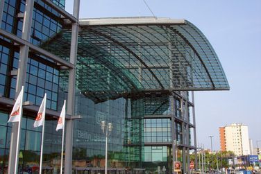 Ein großes Gebäude mit Glasdach ist von Flaggen umgeben.