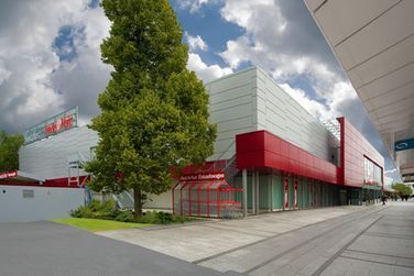 Ein großes Gebäude mit einem roten Dach und einem Baum davor.