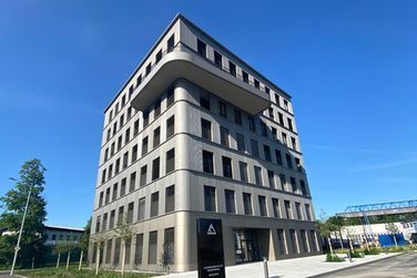 Ein großes Gebäude mit vielen Fenstern und einem blauen Himmel im Hintergrund.