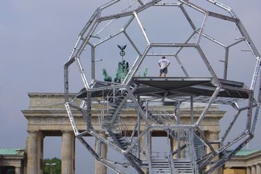 Ein Mann steht auf einer Metallkonstruktion vor einem Gebäude.