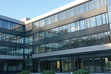 Ein großes Gebäude mit vielen Fenstern und Bäumen davor.