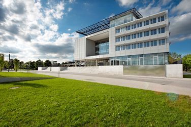 Ein großes weißes Gebäude mit vielen Fenstern steht auf einer üppigen grünen Wiese.