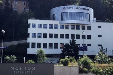 Ein großes weißes Gebäude mit einem Schild mit der Aufschrift Nomos Glashütte