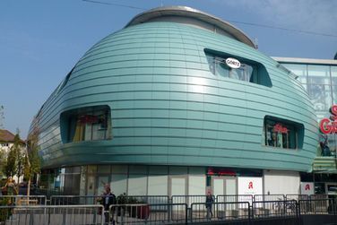 Ein grünes Gebäude mit geschwungenem Dach ist von einem Zaun umgeben.