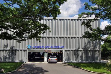 Vor einem großen Gebäude ist ein Auto geparkt.