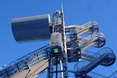 Eine Reihe von Treppen führt zu einem Turm hinauf, im Hintergrund ist ein blauer Himmel zu sehen.