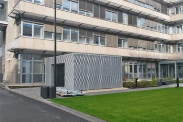 Ein großes Gebäude mit vielen Fenstern und einer Wiese davor.