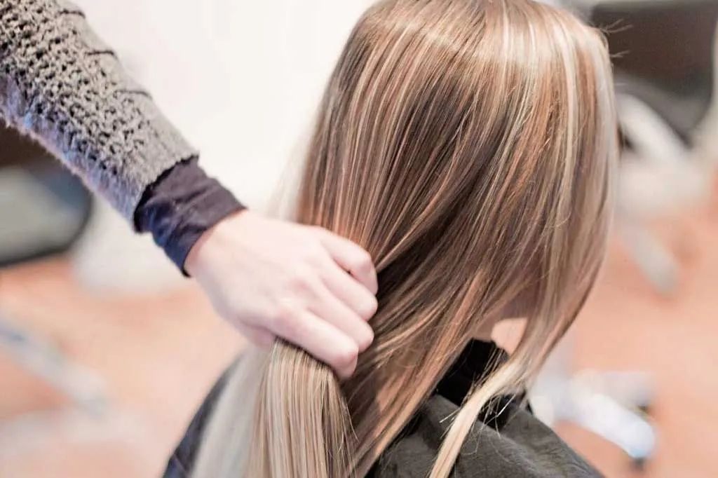 Friseurin präsentiert glatte und gesunde Haare der Kundin