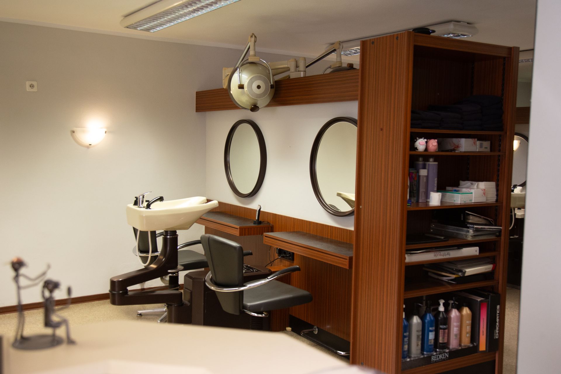 Inneneinrichtung eines Friseursalons mit Frisierplätzen, Spiegeln und Produktregalen.