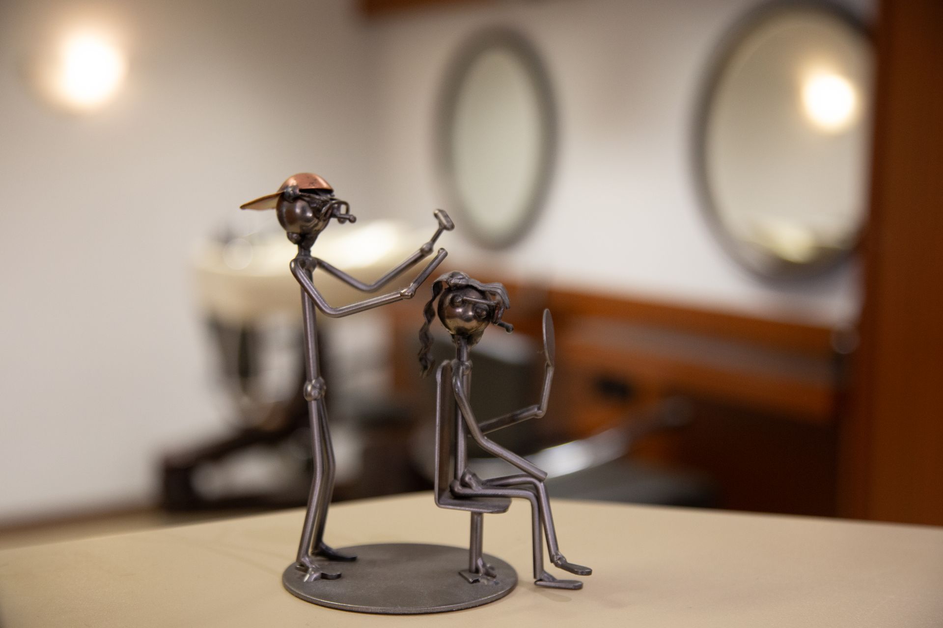 Metallskulptur eines Barbiers, der einem Kunden in einem Friseursalon die Haare schneidet.