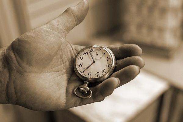 Eine Person hält eine Taschenuhr in der Hand.