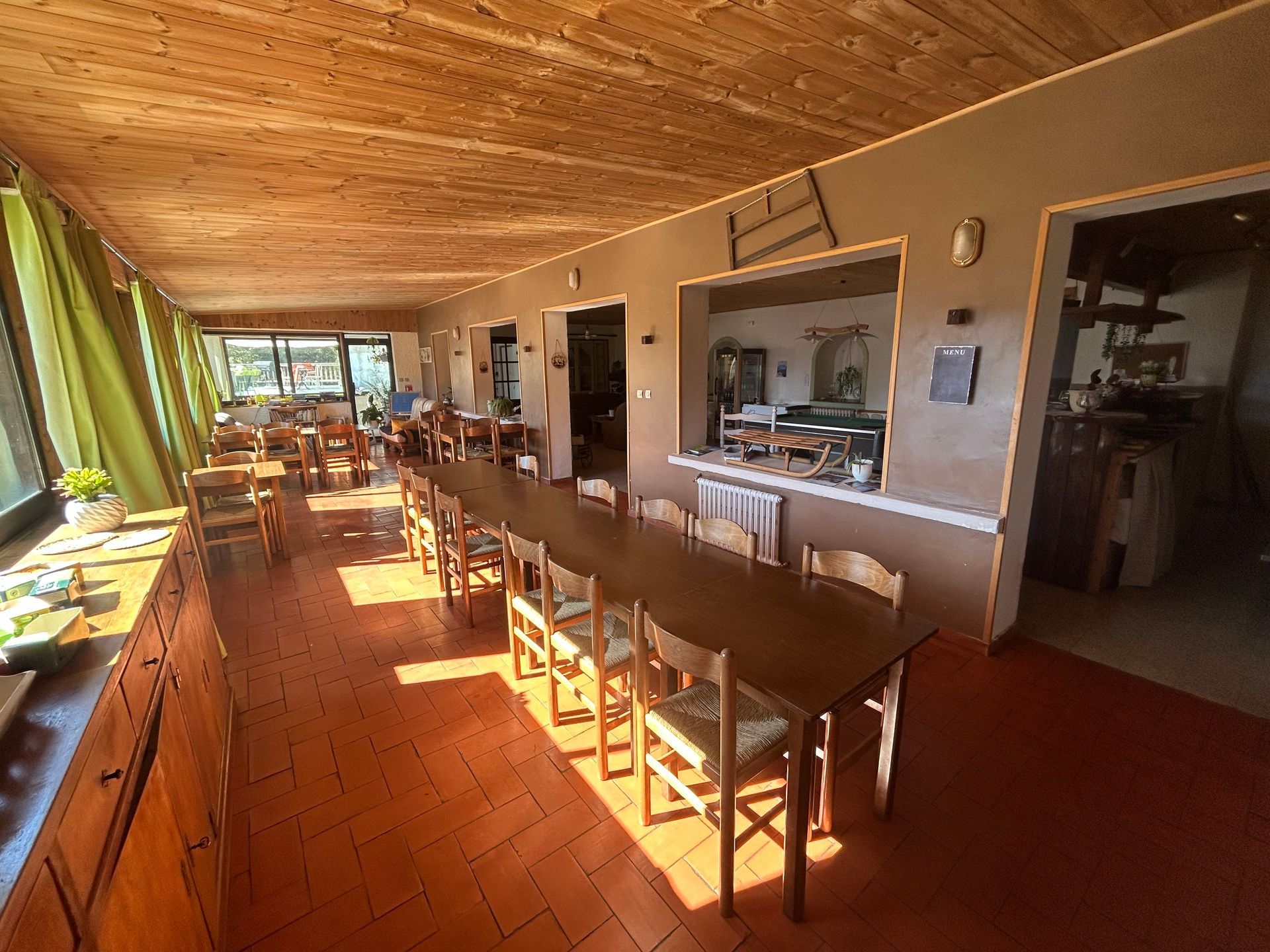 Longue salle à manger avec une table en bois et des chaises.