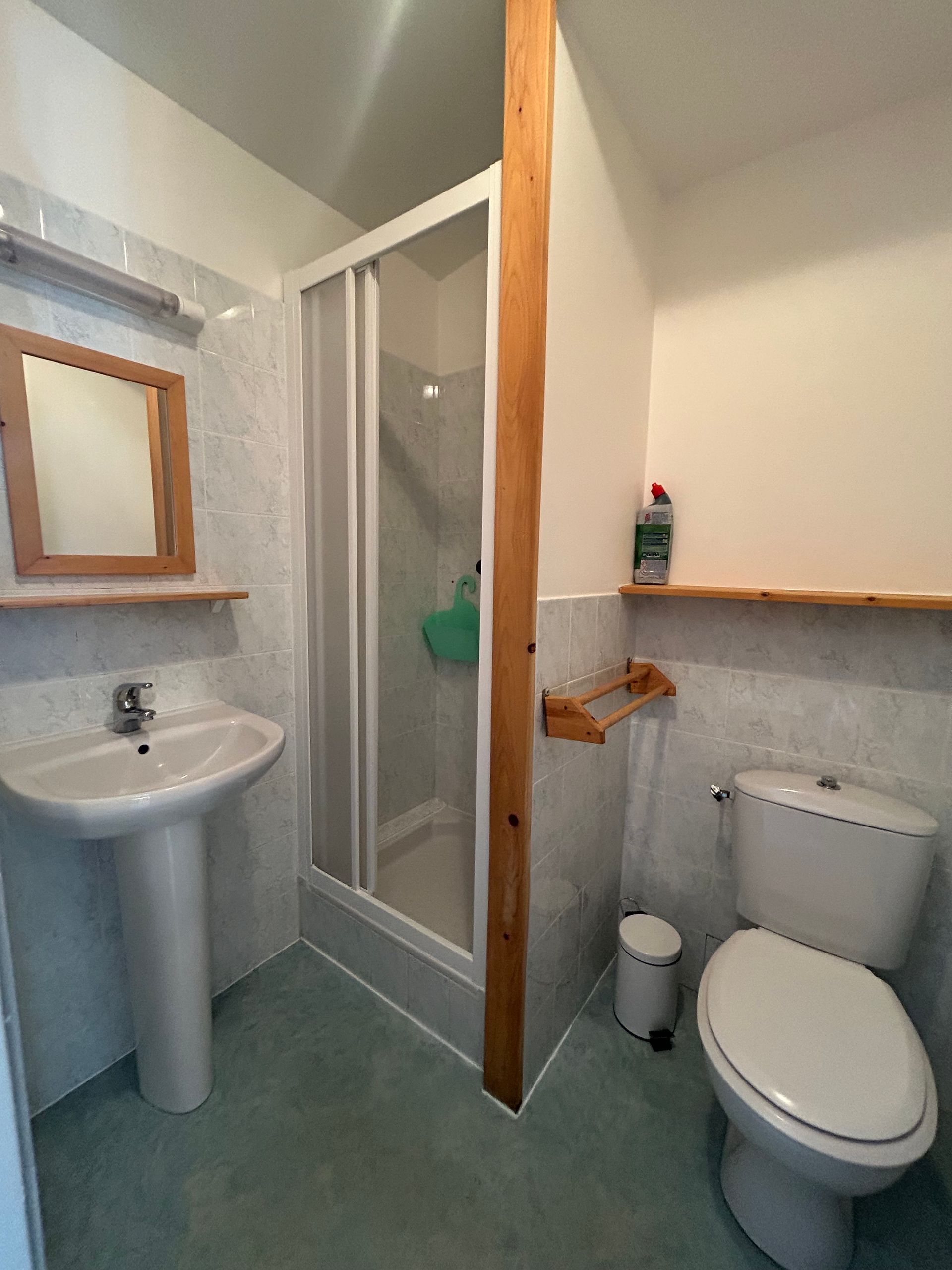 Petite salle de bains avec toilettes, lavabo sur pied et cabine de douche.