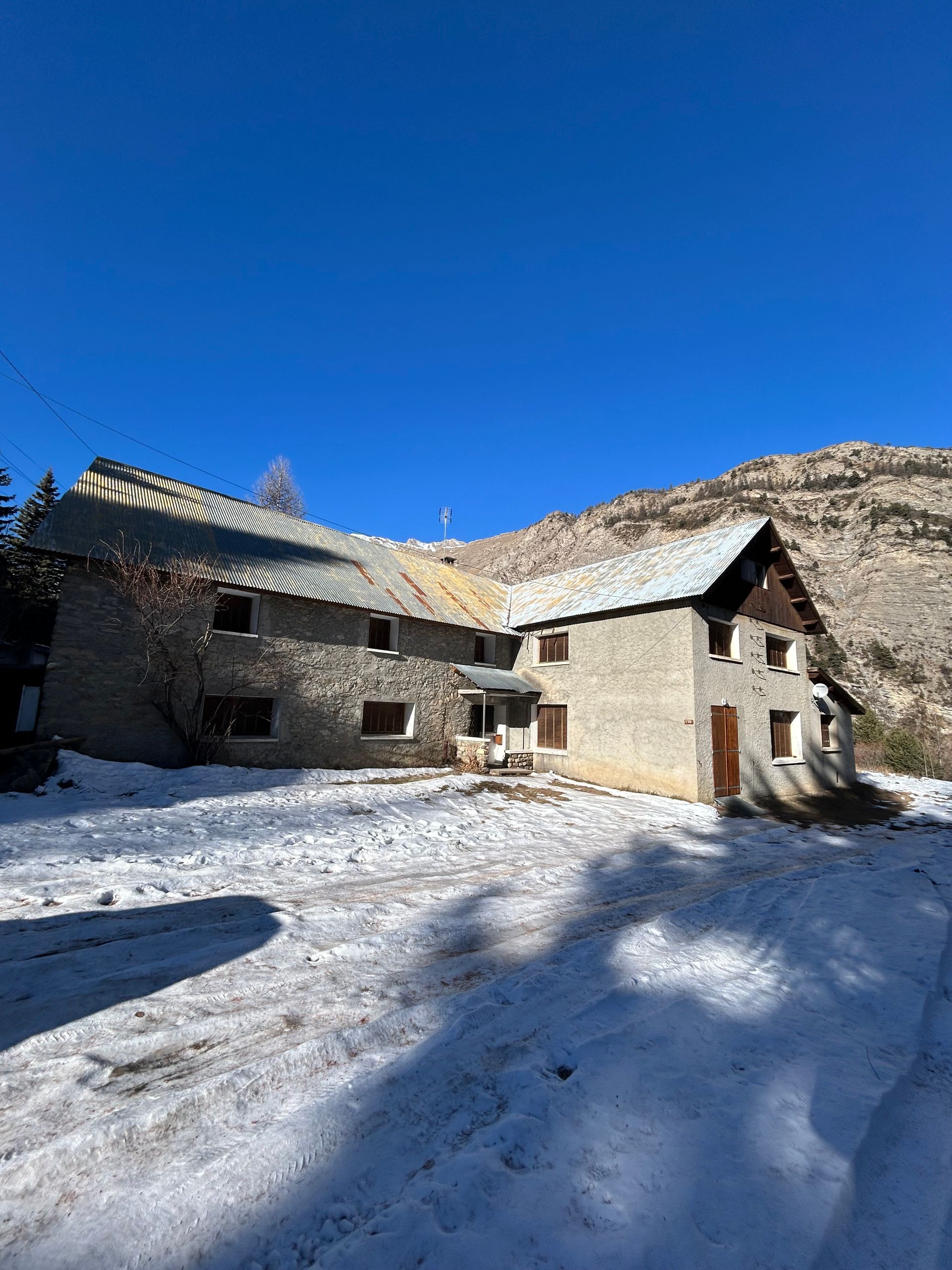 Chalet en pierre enneigé dans un village de montagne.