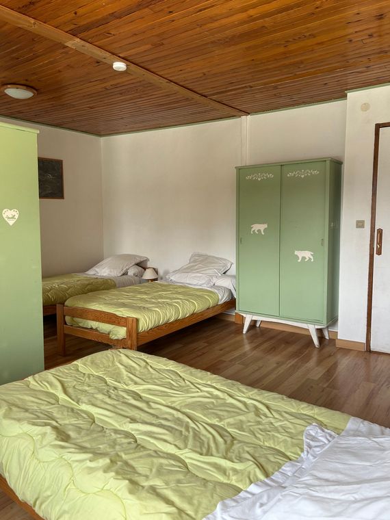 Petite chambre avec deux lits, armoire verte, parquet.