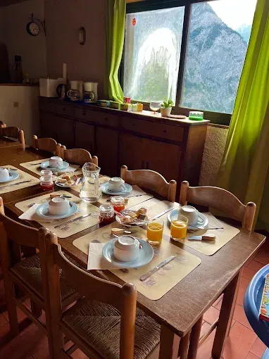 Dresser la table à manger avec de la vaisselle et du jus d'orange près d'une fenêtre dans une salle à manger.