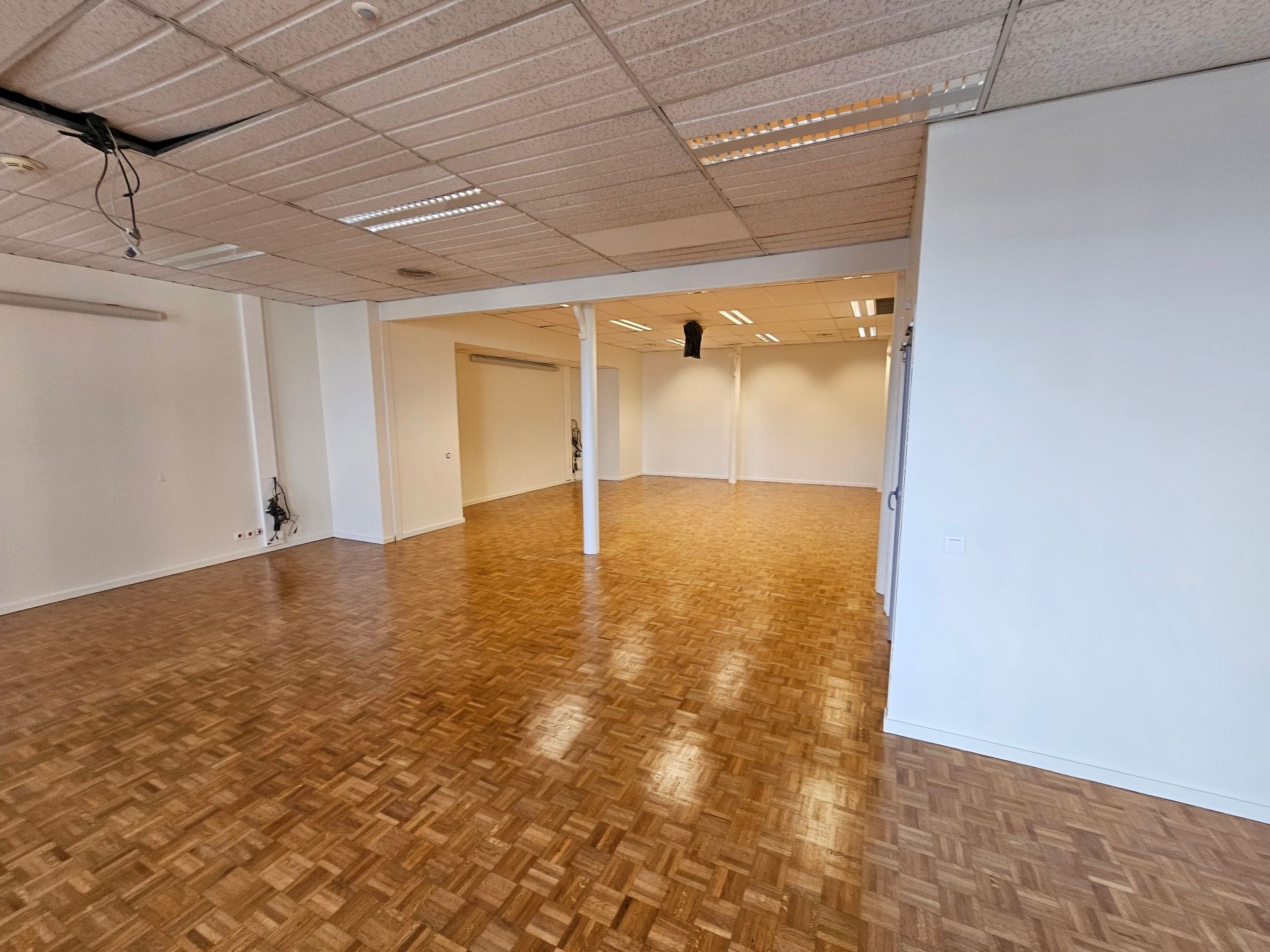 Grande pièce vide avec parquet et murs peints en blanc