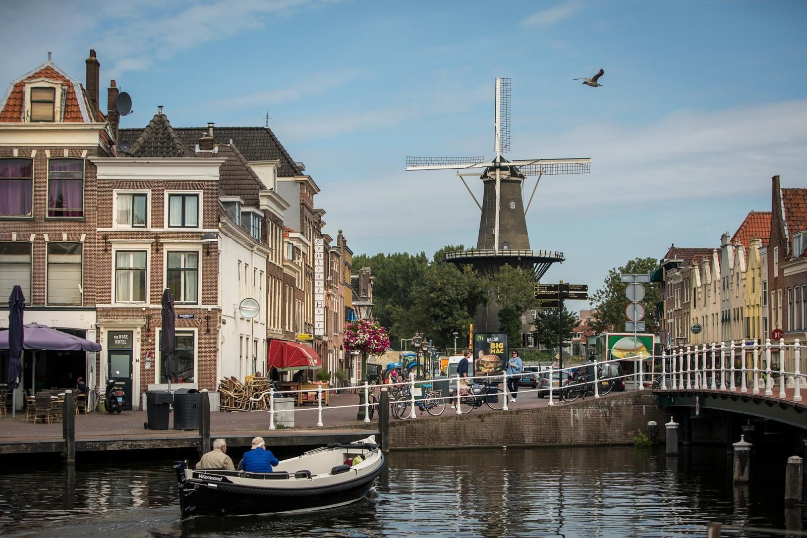 A boat is floating on a river in a city with a windmill in the background.