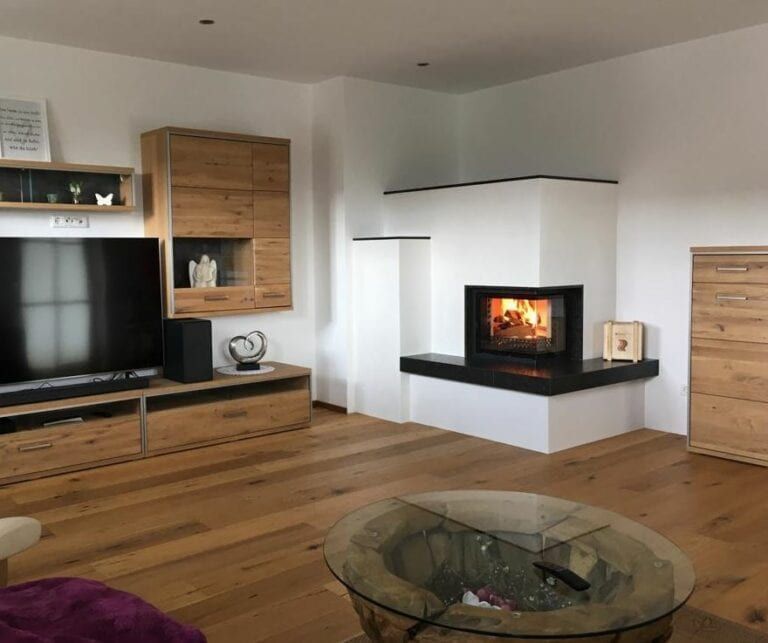 Modernes Wohnzimmer mit Holzboden, weißem Kamin, Flachbildfernseher und Couchtisch aus Glas.