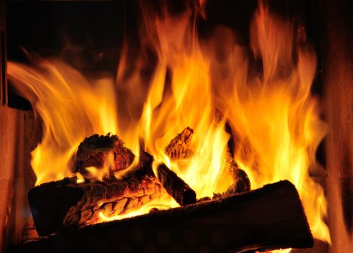 Ein prasselndes Kaminfeuer mit leuchtend orangefarbenen Flammen und glühenden Holzscheiten.