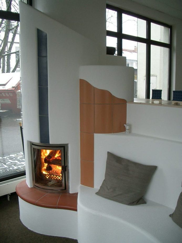 Modernes Wohnzimmer mit brennendem Kamin, geschwungenen weißen Wänden und einem grauen Kissen.