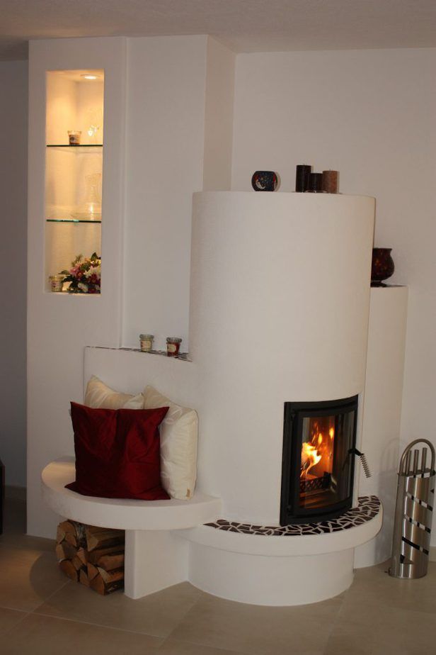 Modernes weißes Wohnzimmer mit geschwungenem Kamin, eingebautem Regal und Sitzkissen.