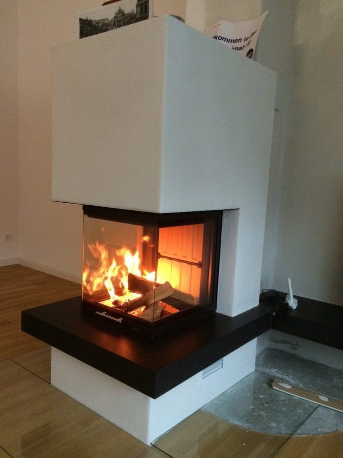 Moderner weißer Eckkamin mit hellem Feuer im Inneren.