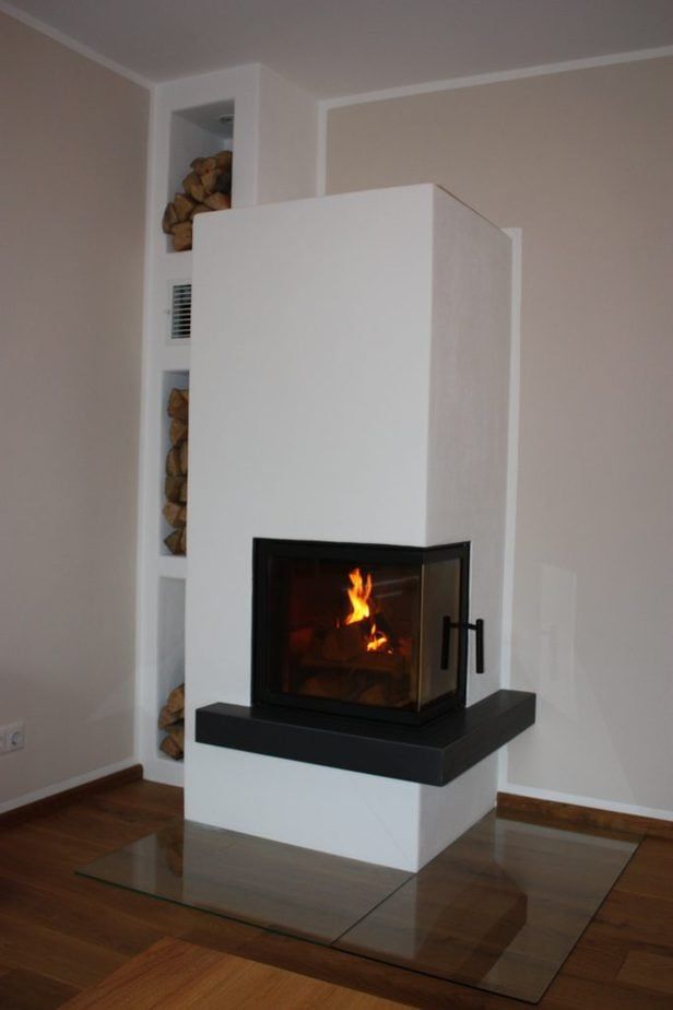 Moderner weißer Kamin mit gläsernem Feuer in einem minimalistisch gestalteten Raum.
