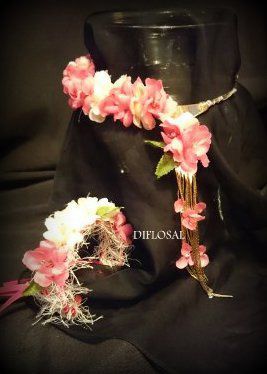 Diadema floral y ramillete de muñeca con flores rosas y blancas sobre fondo negro.