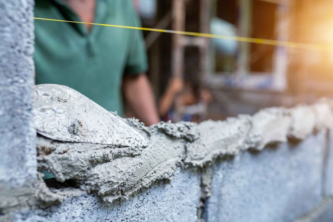 Dos hombres están trabajando en una pared de un edificio en construcción.