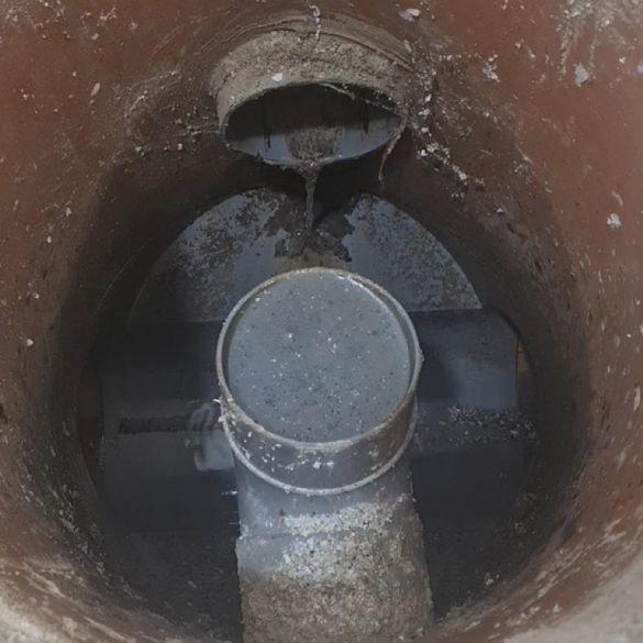 Un primer plano de una tapa de alcantarilla con un tubo que sale de ella.