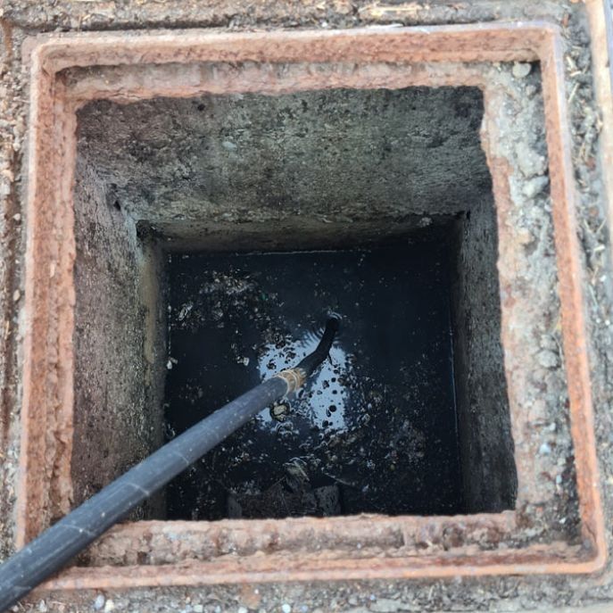 Una tapa de alcantarilla con una manguera que sobresale de ella.