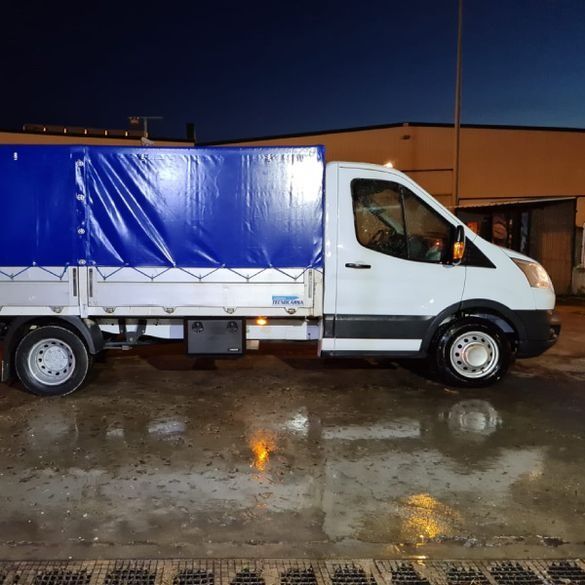 Un camión blanco con una lona azul en la parte trasera está estacionado en un estacionamiento.