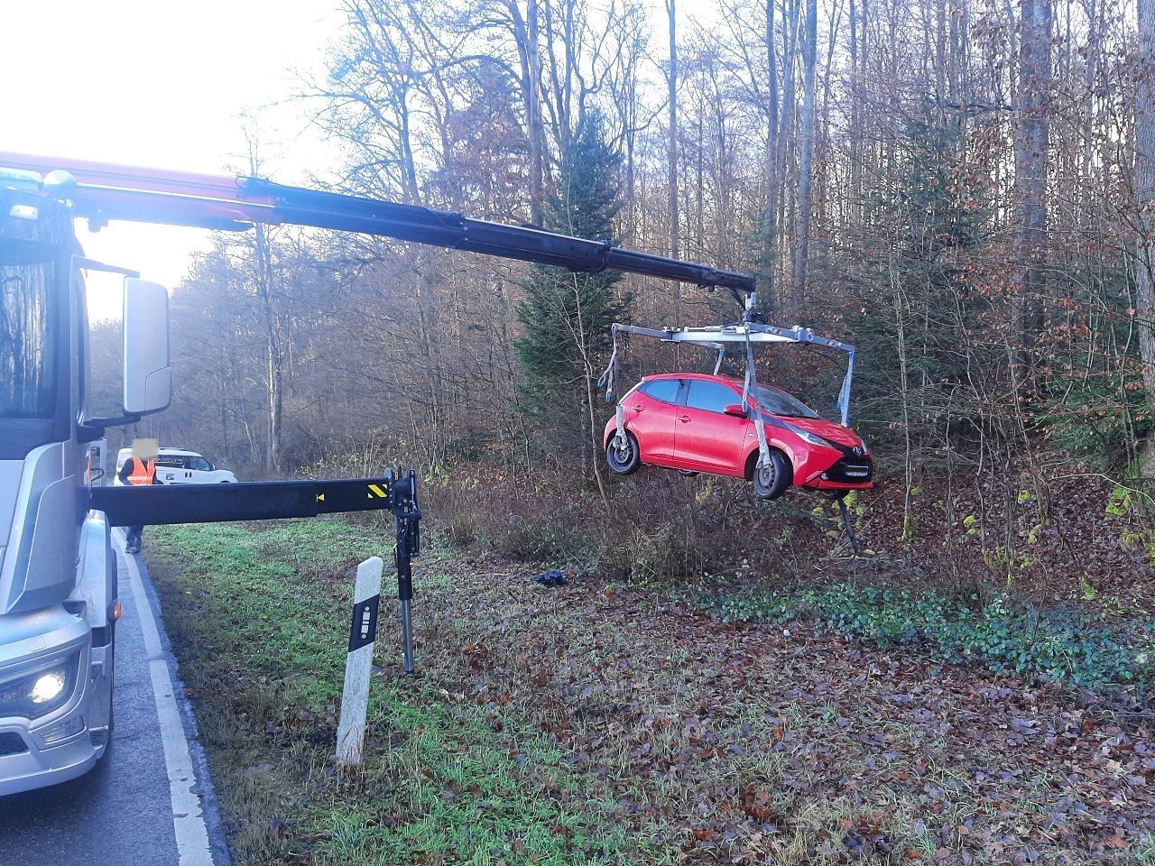 Ein rotes Auto wird von einem Kran angehoben.