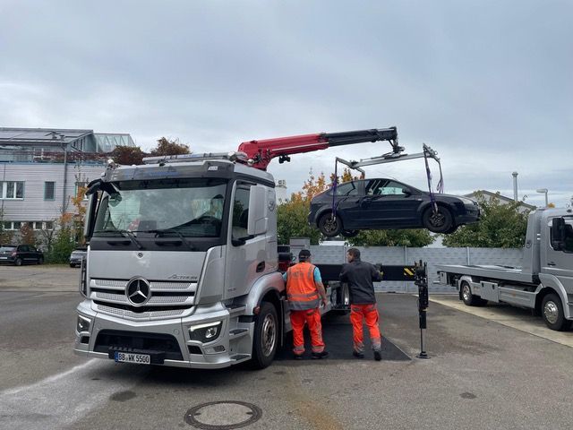 Auf einem Parkplatz wird ein Auto von einem Abschleppwagen abgeschleppt.