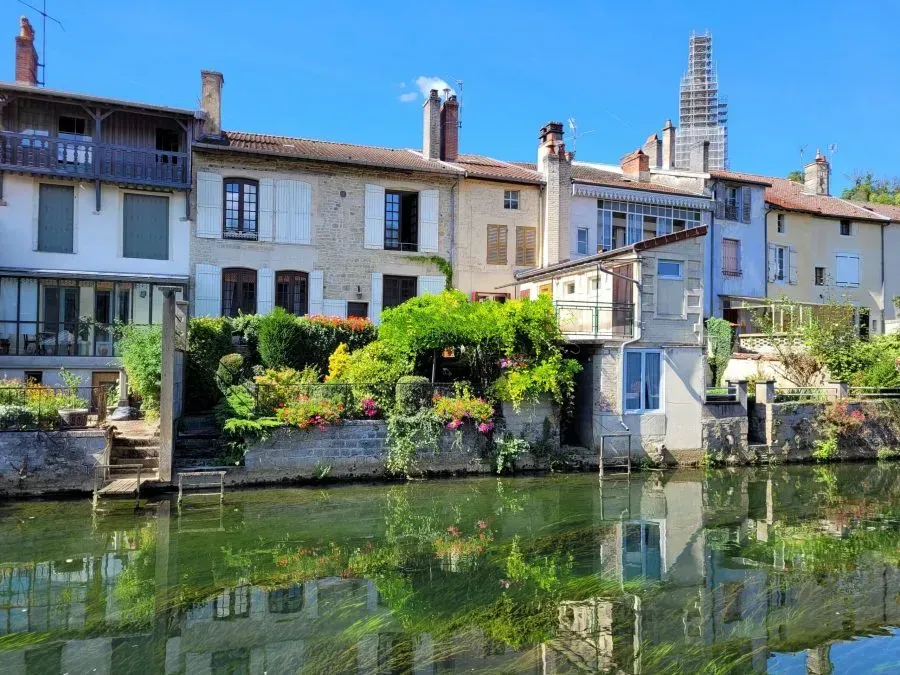 Maisons colorées au bord de la rivière, aux volets verts, se reflétant dans l'eau calme par une journée ensoleillée