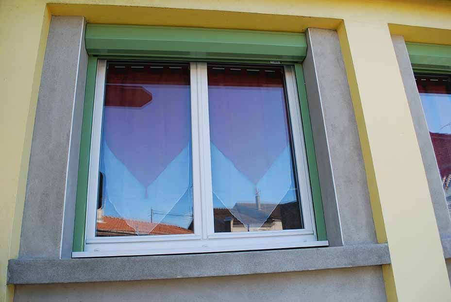 Fenêtre à cadre blanc et auvent vert sur un mur d'immeuble jaune