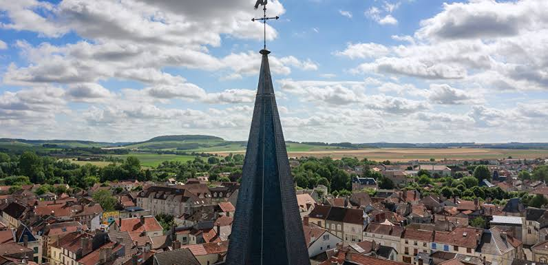Vue depuis le clocher d'une église sur une ville, une campagne verdoyante et un ciel nuageux